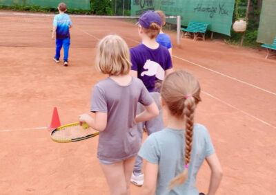 Kinder üben Tennisspielen.